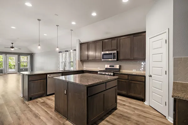 a kitchen with stainless steel appliances granite countertop sink stove top oven and refrigerator