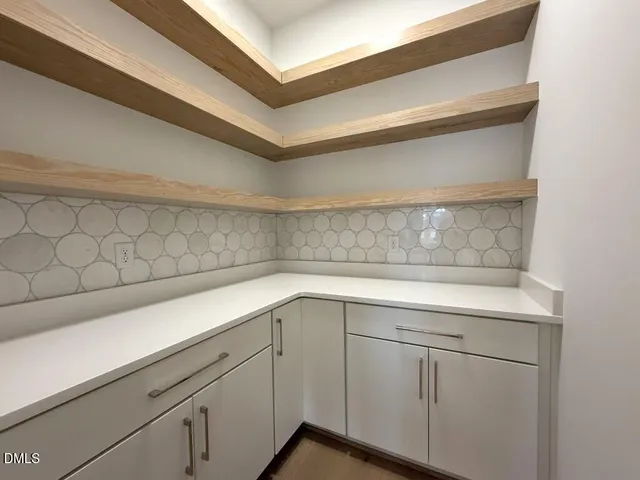 a large kitchen with a large counter top space a sink stainless steel appliances and cabinets