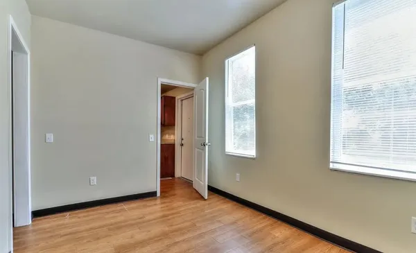 an empty room with wooden floor and windows