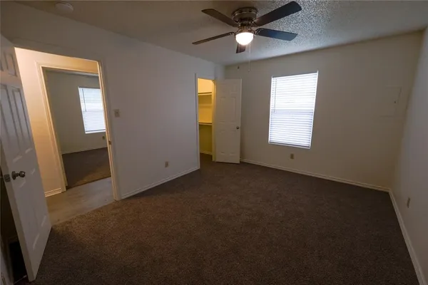 an empty room with windows and fan