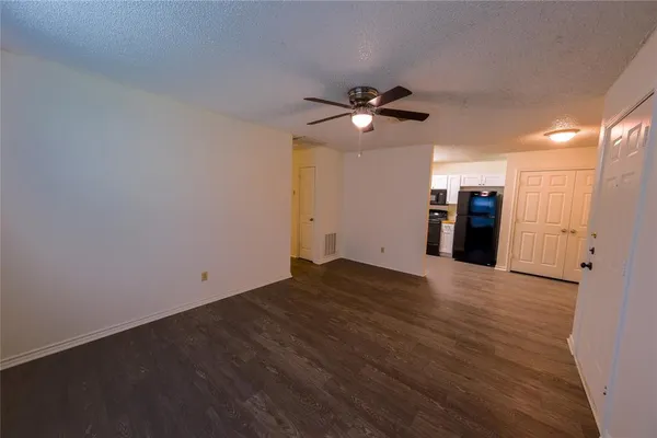 an empty room with wooden floor and ceiling fan