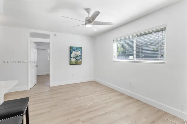 an empty room with wooden floor a ceiling fan and windows