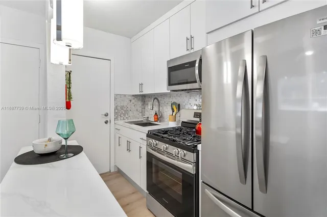 a kitchen with stainless steel appliances a refrigerator sink and white cabinets