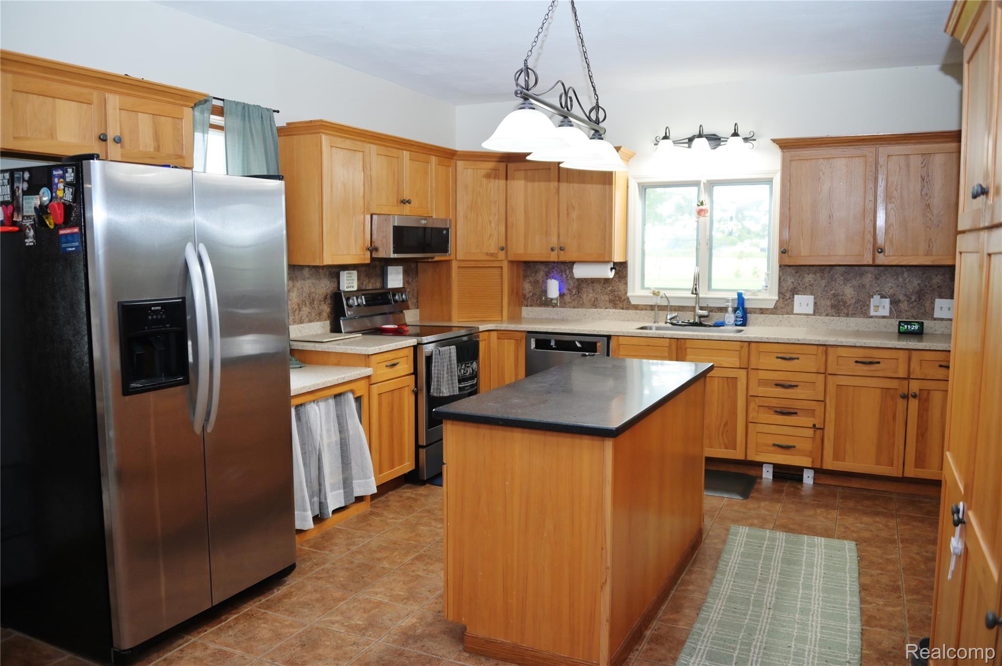 6950 Todd Road Croswell, MI 48422 - Photo 10 of 29 Kitchen with wood cabinetry, stainless steel appliances, a center island with a dark countertop, and tiled flooring