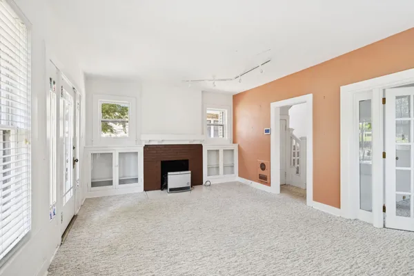 an empty room with windows and fireplace