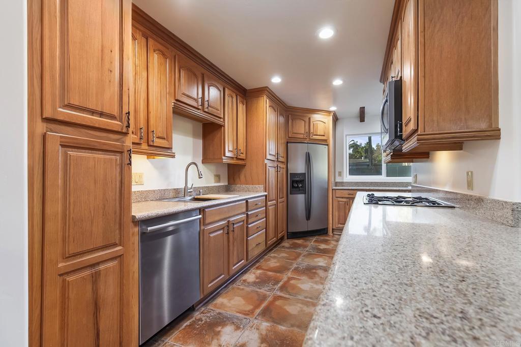 10546 Valle Vista Road Lakeside, CA 92040 - Photo 10 of 66 a kitchen with stainless steel appliances granite countertop a refrigerator a sink dishwasher and wooden cabinets with wooden floor