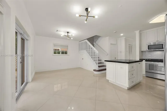 a kitchen with stainless steel appliances granite countertop a refrigerator sink and white cabinets