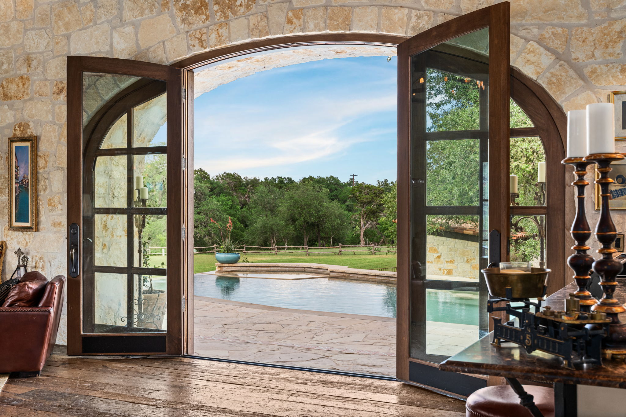 11941 Overlook Pass Austin, TX 78738 - Photo 34 of 40 Double arched glass-paneled doors opening to an outdoor pool with a stone surround