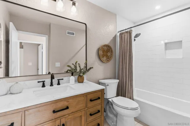 a bathroom with a granite countertop sink toilet mirror and a shower