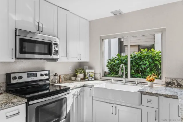 a kitchen with granite countertop a sink stove and microwave
