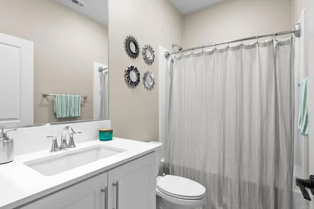 a bathroom with a sink a toilet a mirror and shower curtain
