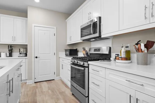 a kitchen with stainless steel appliances granite countertop grey cabinets a stove a sink and dishwasher