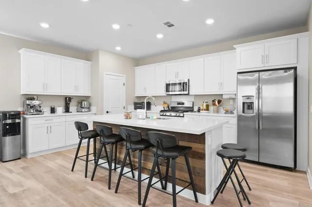 a kitchen with stainless steel appliances a table chairs refrigerator and cabinets