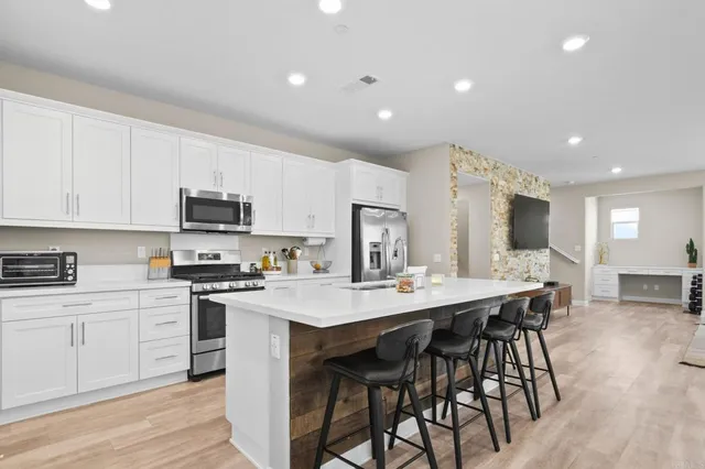 a kitchen with stainless steel appliances a sink a stove a table and chairs