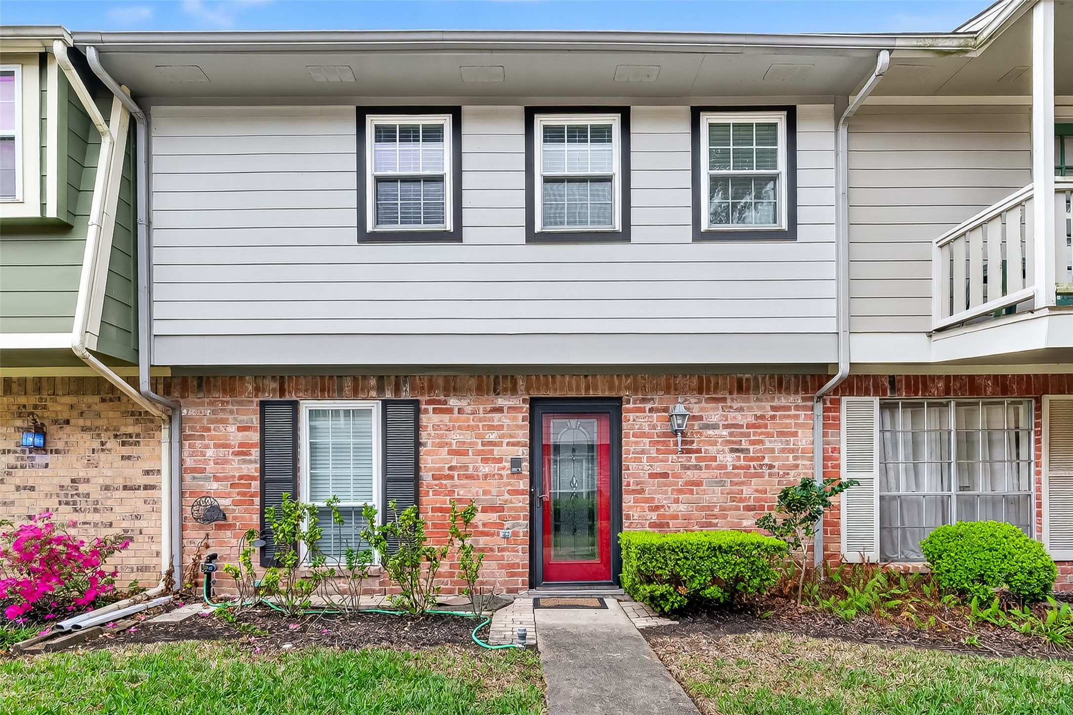 A charming architectural blend of traditional brick and crisp siding, nestled within a lush, established landscape that exudes a sense of quiet permanence.