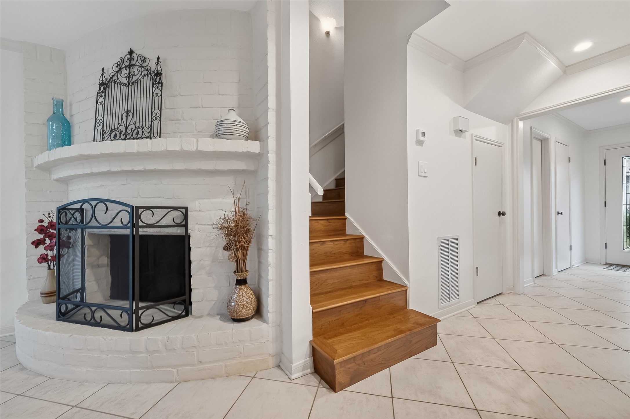 14690 Perthshire Road, Unit C Houston, TX 77079 - Photo 29 of 48 A glossy wood staircase meanders behind the fireplace, tucked within enclosed walls for a sense of privacy and structural intrigue.