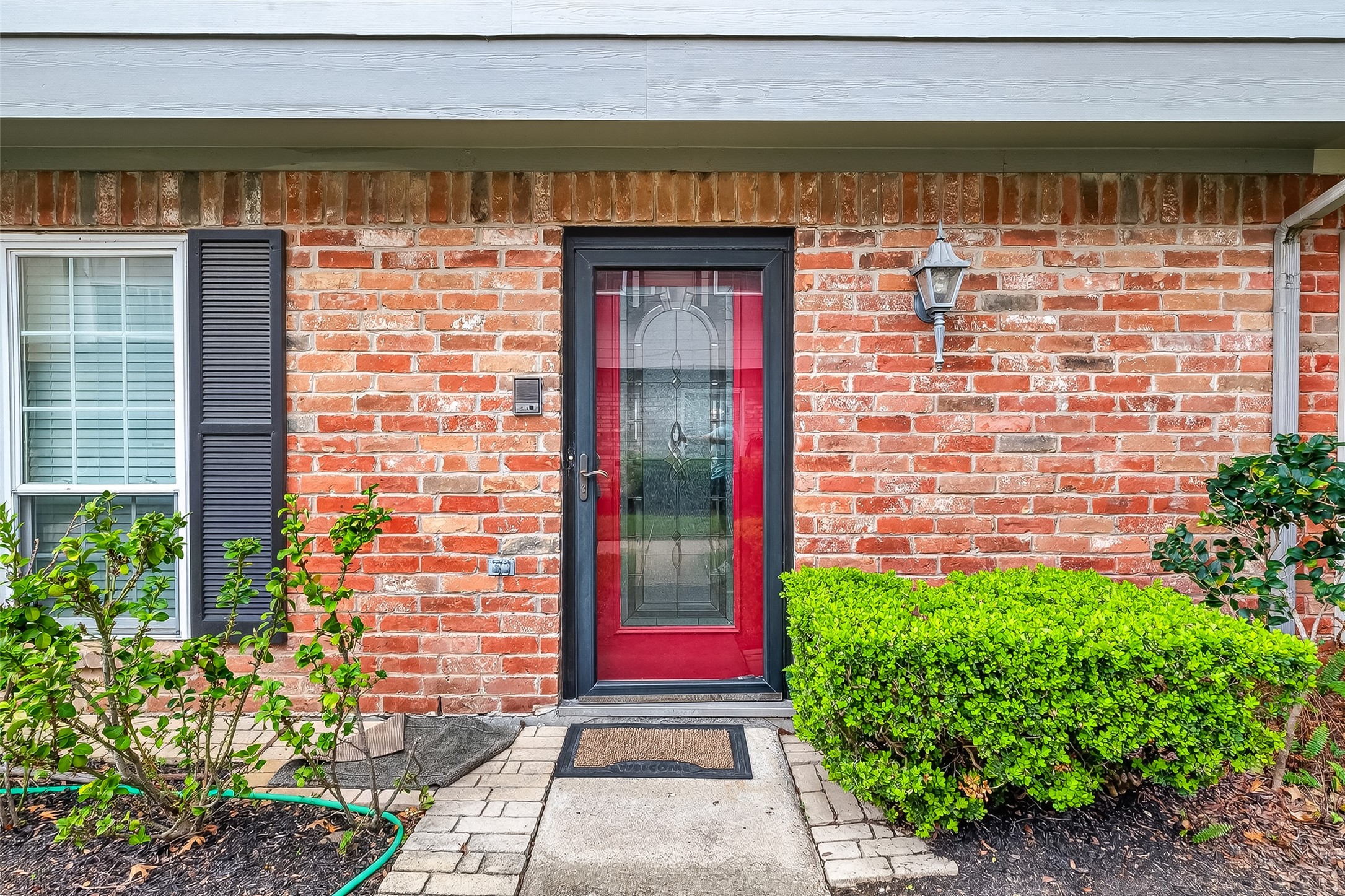 14690 Perthshire Road, Unit C Houston, TX 77079 - Photo 5 of 48 The bold red front door serves as a vibrant focal point, flanked by a sconce and window shutters for a touch of timeless character.