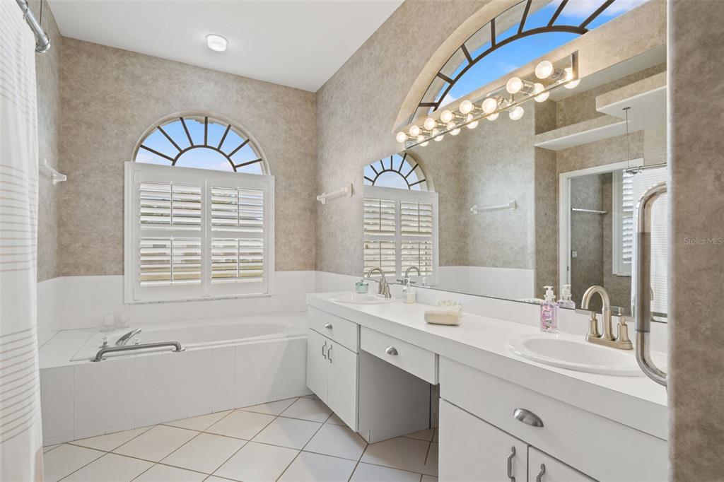 8405 Maybelle Drive Weeki Wachee, FL 34613 - Photo 31 of 61 a bathroom with a double vanity sink mirror and a bathtub with shower