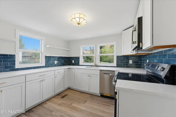 a kitchen with cabinets appliances a sink and a window