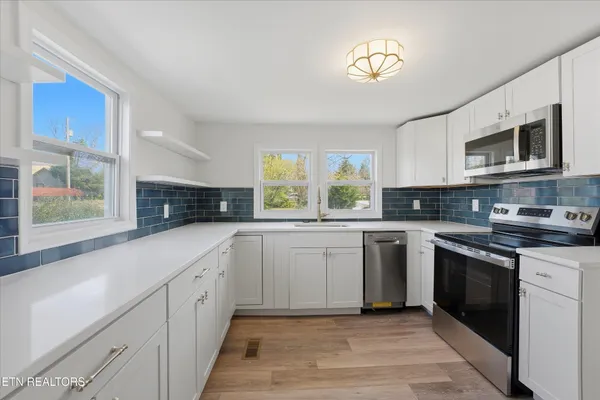 a kitchen with stainless steel appliances granite countertop a stove sink and cabinets