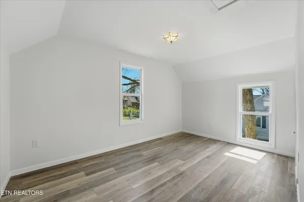 an empty room with wooden floor and window