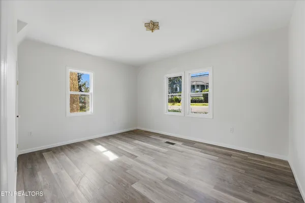 an empty room with wooden floor and windows