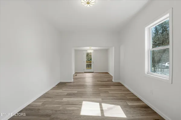 a view of an empty room with wooden floor and a window