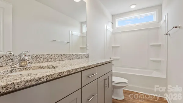 a bathroom with a granite countertop sink a toilet and shower