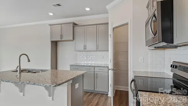 a kitchen with a sink and a stove top oven with wooden floor