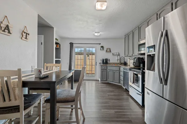 a kitchen with granite countertop stainless steel appliances a refrigerator a stove a dining table and chairs