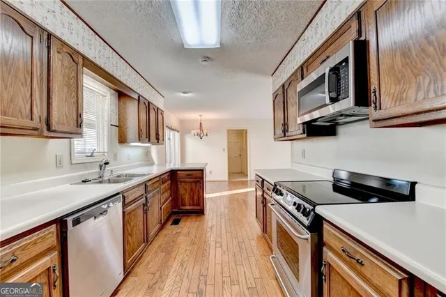 a kitchen with kitchen island granite countertop a stove top oven a sink and dishwasher a oven with wooden floors