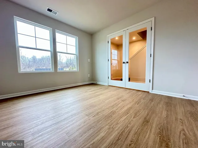 an empty room with wooden floor and windows