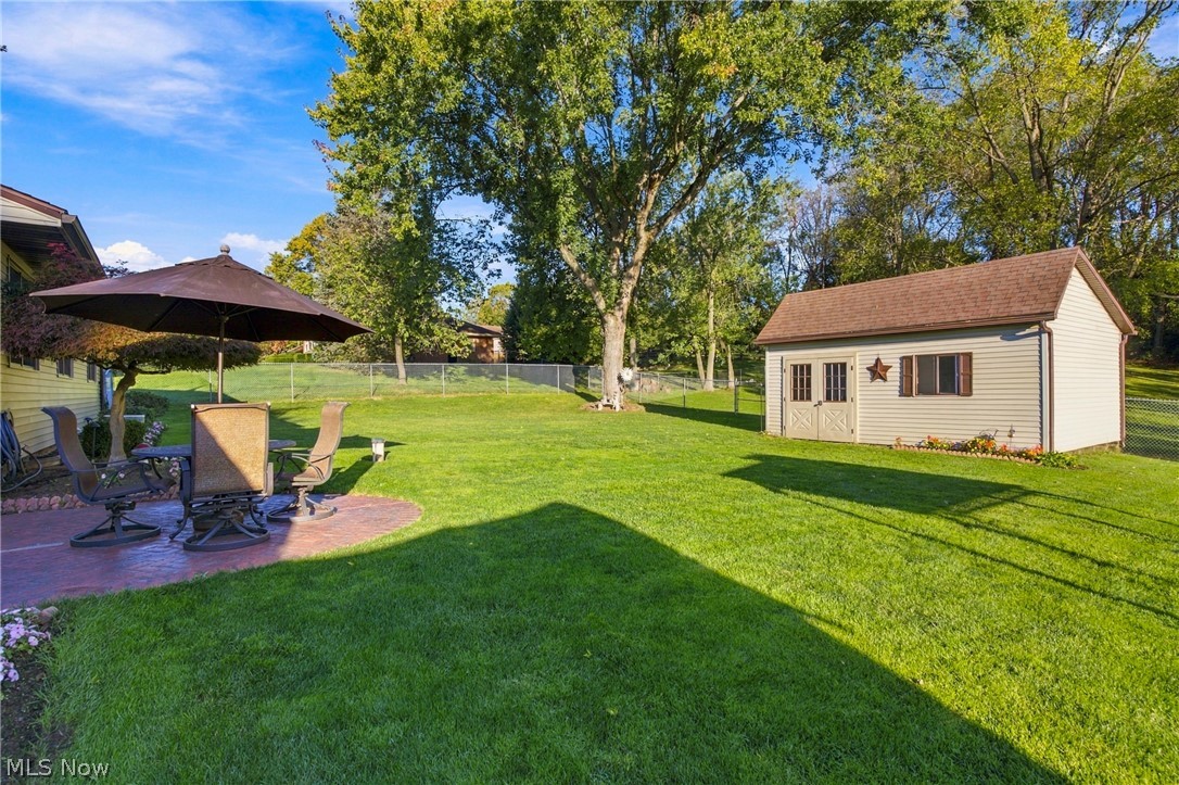 1211 Etter Road Mogadore, OH 44260 - Photo 17 of 48 Expansive lawn featuring a detached shed with double doors and a window, a circular stamped concrete patio, and mature trees