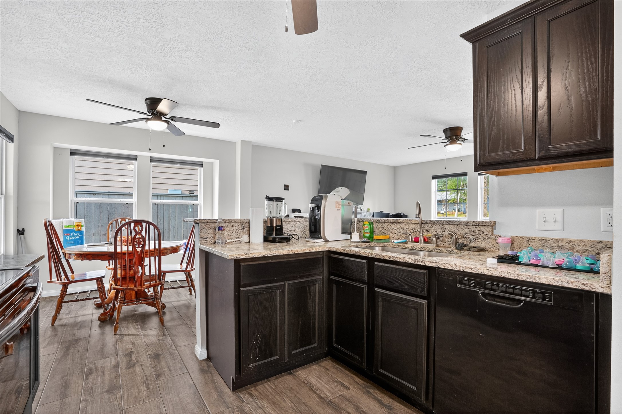 14986 Crockett Road Willis, TX 77378 - Photo 4 of 16 a kitchen with stainless steel appliances granite countertop a sink dishwasher a stove dining table and chairs with wooden floor