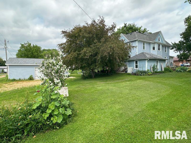 605 Fulton Street Grand Mound, IA 52751 - Photo 2 of 16 a view of a house with a big yard and large trees