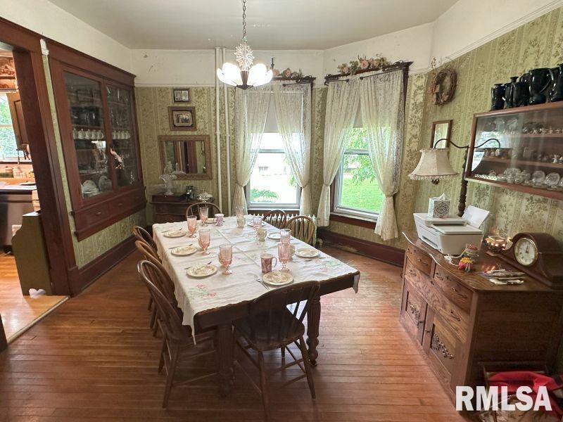 605 Fulton Street Grand Mound, IA 52751 - Photo 7 of 16 a dining room with wooden floor a chandelier a wooden table and chairs