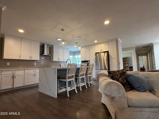 a living room with furniture a dining table wooden floor and kitchen view