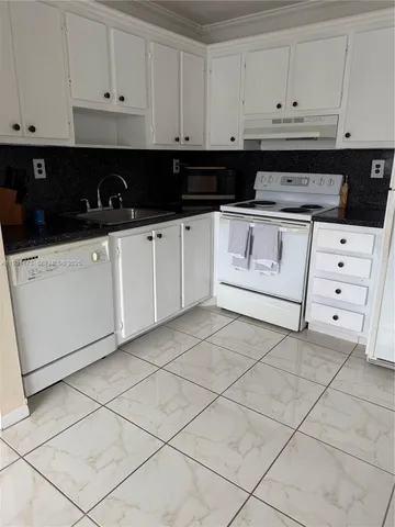 a kitchen with white cabinets and appliances