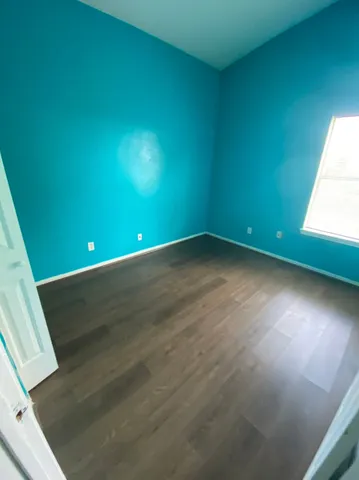 a view of an empty room with wooden floor and windows