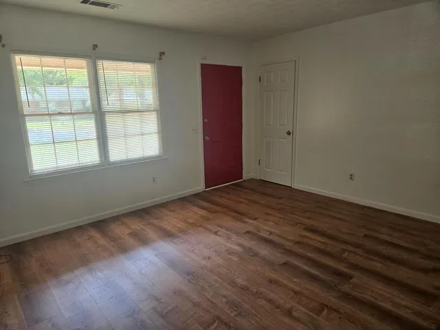 an empty room with wooden floor and windows