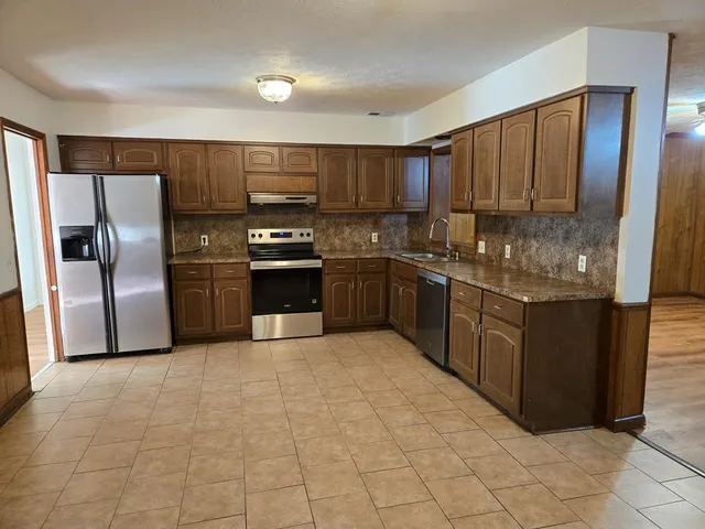 a kitchen with stainless steel appliances granite countertop a refrigerator and a sink