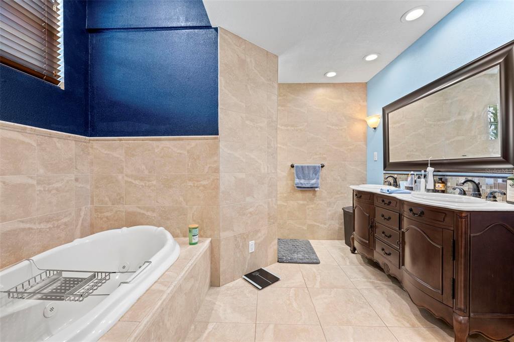 14207 Cornewall Lane Spring Hill, FL 34609 - Photo 51 of 63 a spacious bathroom with a double vanity sink a mirror and a bathtub