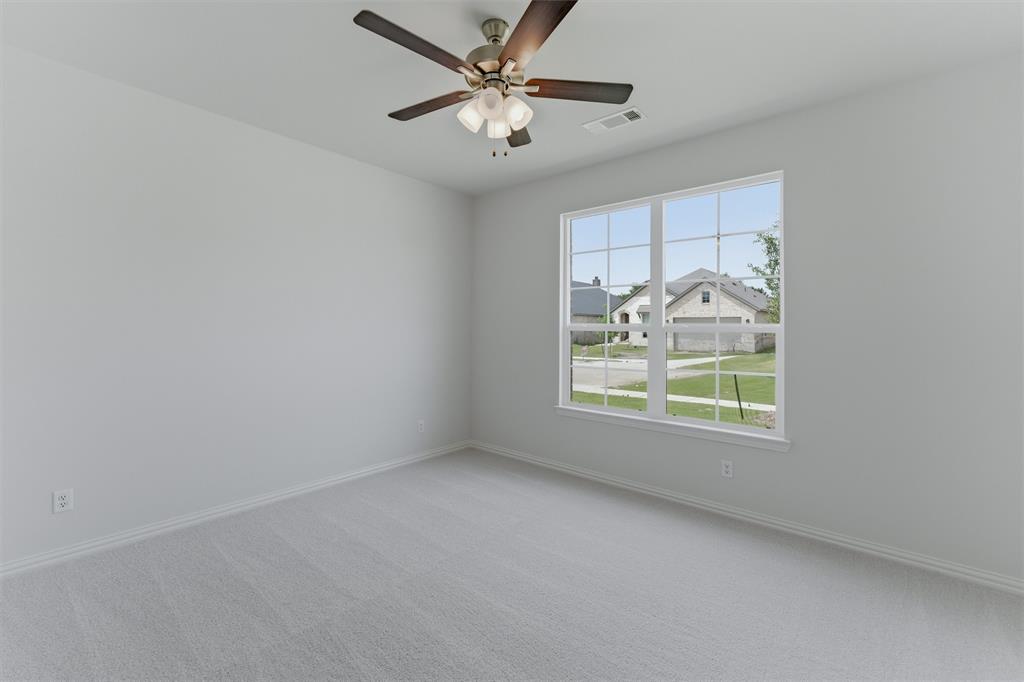 3504 Helena Street Gainesville, TX 76240 - Photo 6 of 19 Carpeted interior space featuring a multi-pane window with white trim, a ceiling fan with integrated lighting, and neutral wall tones