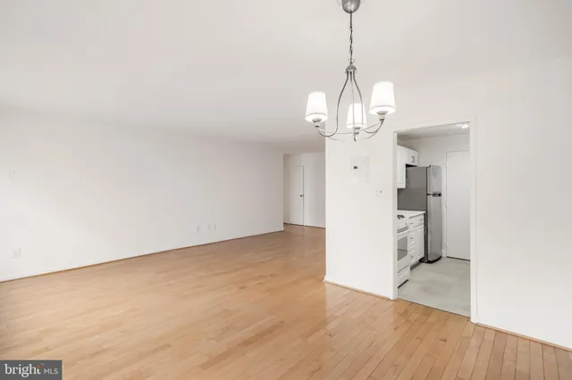 a view of a room with wooden floor refrigerator and windows