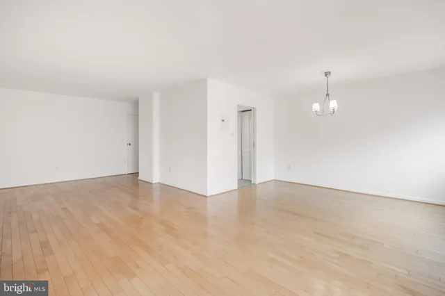 an empty room with wooden floor and ceiling fan