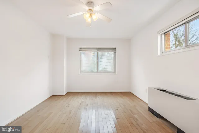 an empty room with wooden floor chandelier fan and windows