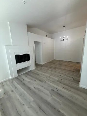 a view of empty room with wooden floor and kitchen