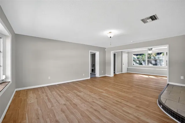 a view of an empty room with wooden floor and a window