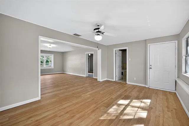 a view of an empty room with wooden floor and a window