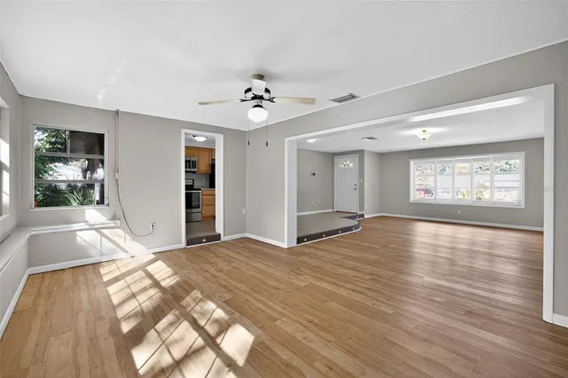 a view of an empty room with window and wooden floor